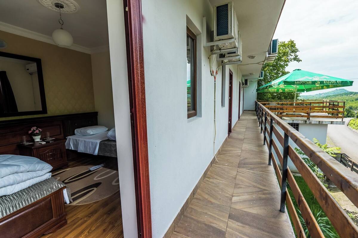 A hotel room with a balcony, a bed, a bedside table, and a window.