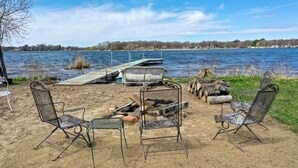 Un espace extérieur aménagé au bord du lac, avec des chaises en métal et un foyer.