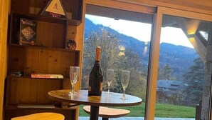 A cozy interior with wooden walls, a wooden bar area, and a large window offering a mountain view. - Chalet neuf standing Samoëns - Adults only (15+) (Samoëns)
