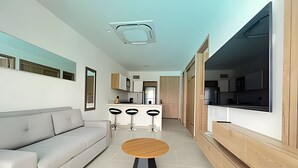 Ein modernes Wohnzimmer mit einer Couch, einem runden Holztisch und einem an der Wand befestigten Fernseher.