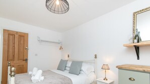 Et soveværelse med seng, sengebord, kommode og en hængende lampe.
