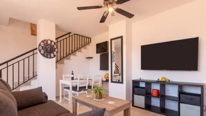 Una sala de estar moderna con un sofá, una mesa de centro, un televisor, una escalera y un comedor.