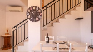 Un interior moderno con una escalera, una zona de comedor con mesa y sillas, y un reloj en la pared.