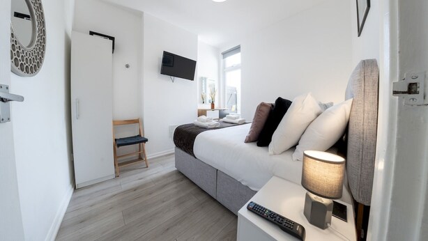 Et moderne hotelværelse med en seng, et skrivebord med lampe, et fjernsyn og et vindue.