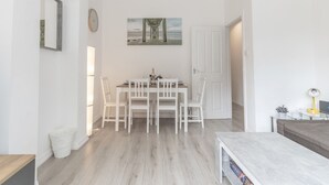 Et spiseområde med et hvidt bord og stole, et billede på væggen og en dør, der fører til et andet rum.