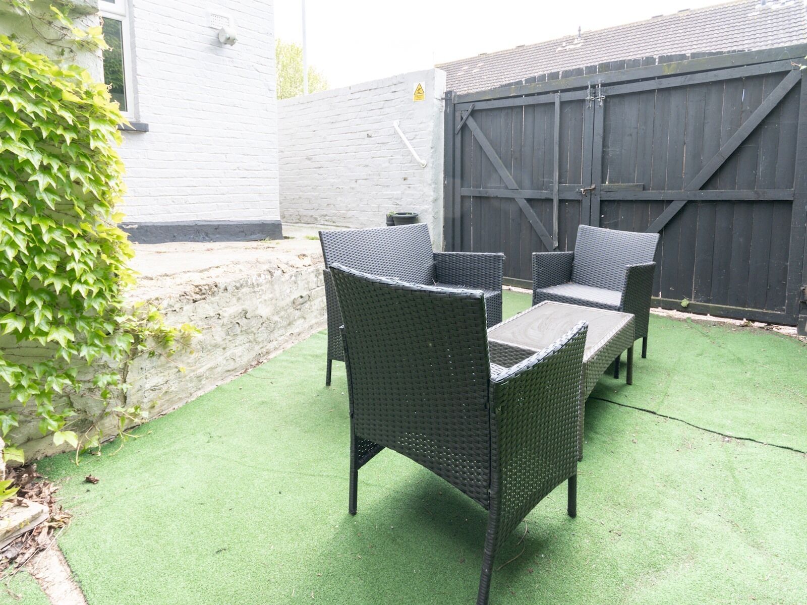 A patio with wicker furniture and artificial grass.