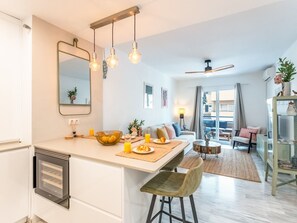 Una cuina moderna amb una illa central, una zona de menjador amb sofà, i un saló amb vistes.