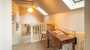 Un comedor con una mesa de madera, sillas y vistas al exterior por un tragaluz.