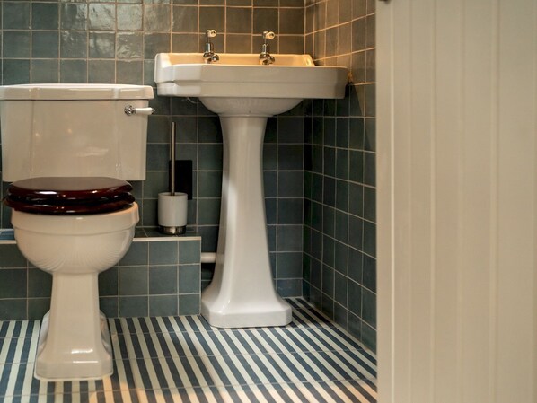 A bathroom with a toilet, a pedestal sink, and a striped floor.