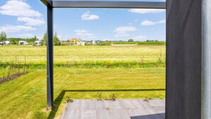 A view from a room with a large window overlooking a grassy field and distant buildings. - Tranquil Holiday Home With Views (Oud Ade)