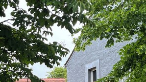 Une maison dotée d’une pergola en bois, d’un jardin et offrant une vue sur un bâtiment voisin.