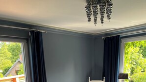Une chambre à coucher avec un lit, une chaise, un radiateur et une fenêtre avec des rideaux.