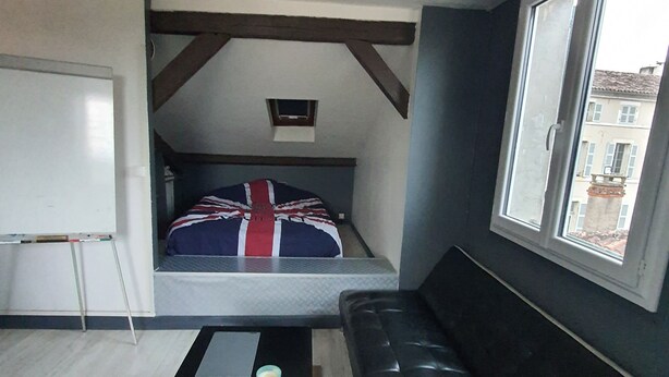 A compact room with a bed, a black leather sofa, a small table, and a whiteboard. - Charming apartment in downtown Cahors (Cahors)