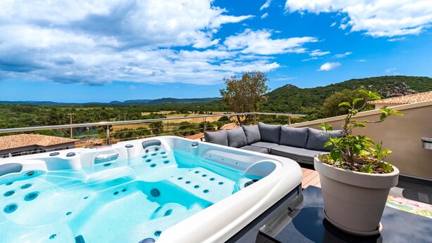Eine Dachterrasse mit Whirlpool, Sitzgelegenheit im Freien und einer Topfpflanze.
