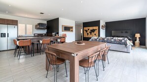 Eine moderne Küche mit Kochinsel, Barhocker und einem Esstisch mit Stühlen.