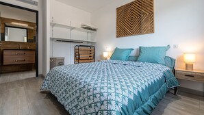 Ein Schlafzimmer mit einem Bett, einem Nachttisch, einem Wandregal, einer hölzernen Kommode und einem Spiegel.