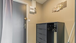 A room with a grey door, a wardrobe with multiple drawers, a power outlet, and a wall-mounted electrical box. - Le Cocon Vendéen - Vue Mer (Saint-Hilaire-de-Riez)