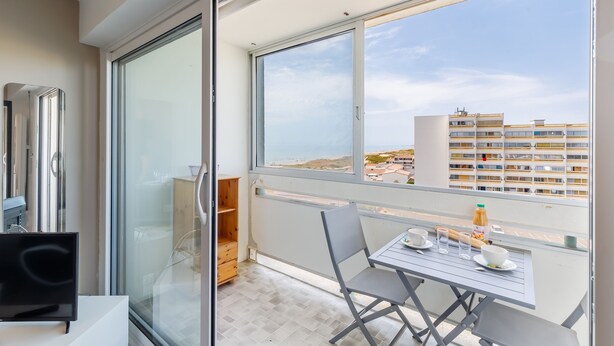 A balcony with a table, chairs, and a TV. - Le Cocon Vendéen - Vue Mer (Saint-Hilaire-de-Riez)