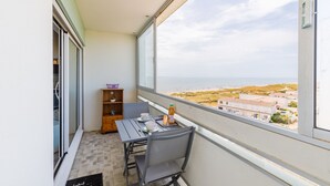 A balcony with a table, chairs, and a view of the beach and buildings. - Le Cocon Vendéen - Vue Mer (Saint-Hilaire-de-Riez)
