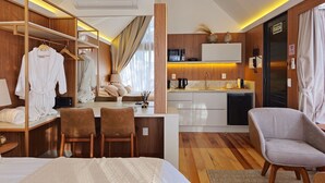 Ein modernes Hotelzimmer mit Bett, Schreibtisch mit Stuhl, Kleiderschrank, Bad und einer Küchenzeile.