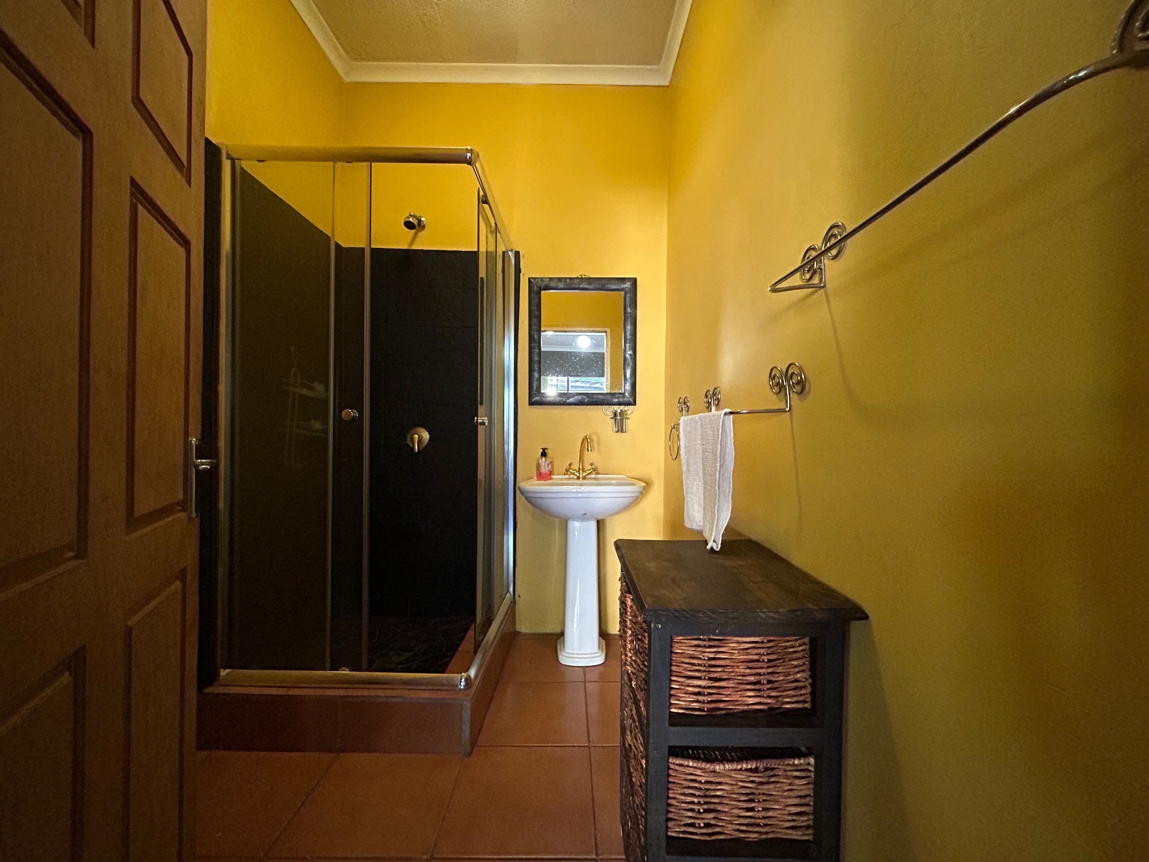 Een badkamer met een douchecabine van glas, een wit wastafelmeubel en een spiegel erboven.