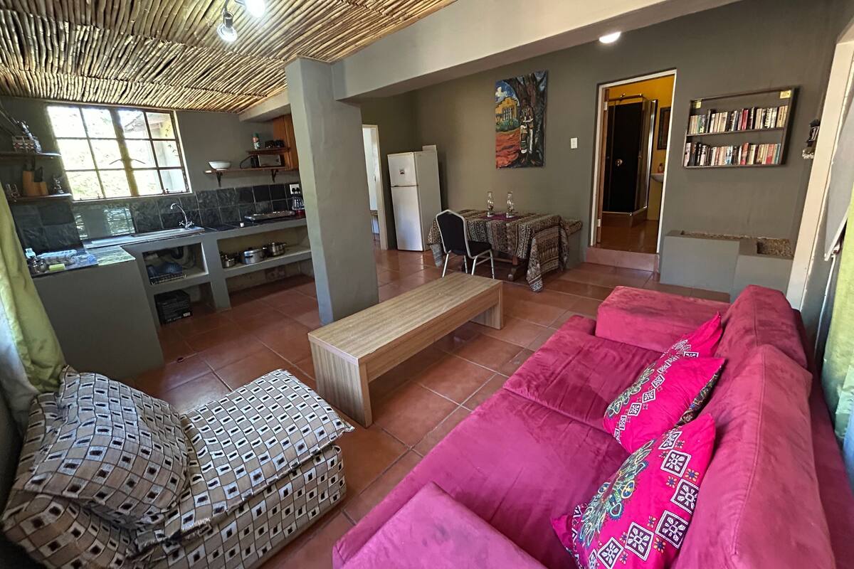 A spacious living area with a sofa, ottoman, and a dining table set for two.