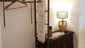 Ett rustikt rum med ett träställ för att torka kläder, en flätad lampa och en trälåda.