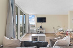 A modern living room with a sofa, a coffee table, and a dining area with chairs and a table.