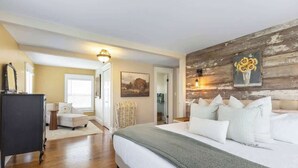 A bedroom with a bed, a dresser, a chair, and a painting on the wall.