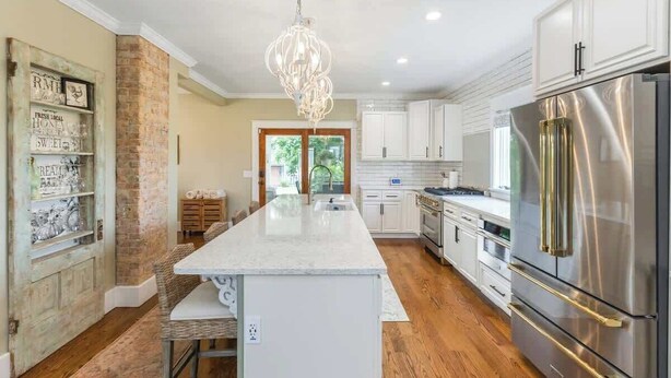 A modern kitchen with a central island, stainless steel appliances, and a hanging light fixture.