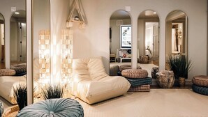 A modern living room with a sofa, ottomans, a large mirror, and a hanging light fixture.