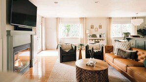 A living room with a fireplace, a sofa, a coffee table, and a TV mounted on the wall.