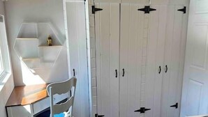 A bedroom with a bed, a desk with a chair, and a wardrobe with two doors. - Cozy Coastal Cabin w/Hot Tub (Valley Road)