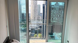 A bedroom with a large bed, a view of the city through a sliding glass door, and a modern interior design. - Luxury Stay with Scenic Views (London)