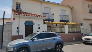A building with a tiled roof, a balcony with a railing, and a car parked in front. - Come and stay in Marifé's house, two bedrooms available at 17 km from Seville. (Villanueva del Ariscal)