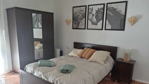 A bedroom with a bed, a wardrobe, a nightstand, and three framed pictures on the wall. - Come and stay in Marifé's house, two bedrooms available at 17 km from Seville. (Villanueva del Ariscal)