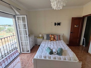 Une chambre à coucher avec un lit, une table de chevet, un jouet en peluche, une serviette et un balcon.