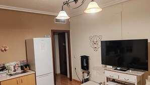 A compact kitchen with a refrigerator, a dining table, and a TV on a stand. - Come and stay in Marifé's house, two bedrooms available at 17 km from Seville. (Villanueva del Ariscal)
