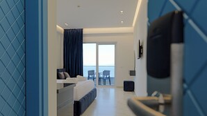 Een moderne hotelkamer met een bed, een zithoek met uitzicht op zee en een balkon.