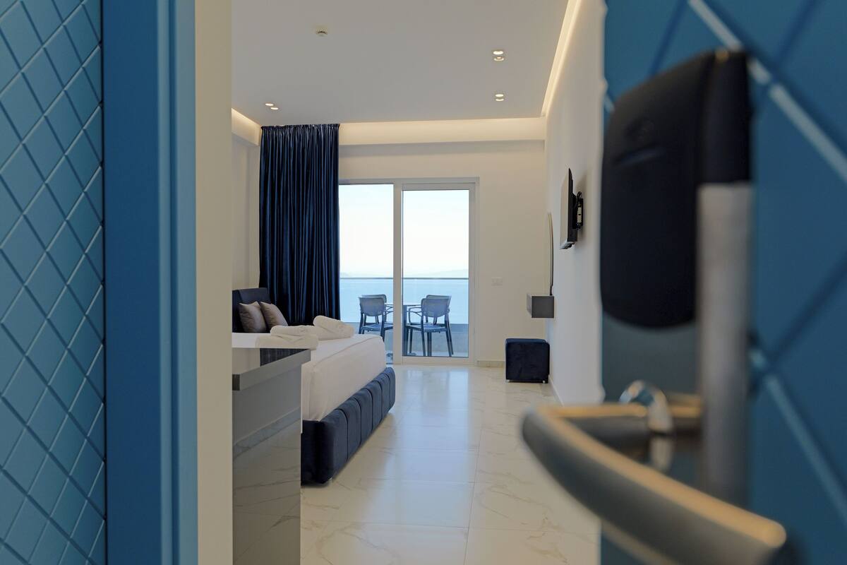 Una habitación de hotel moderna con cama, zona de estar y vistas al mar, además de un balcón.