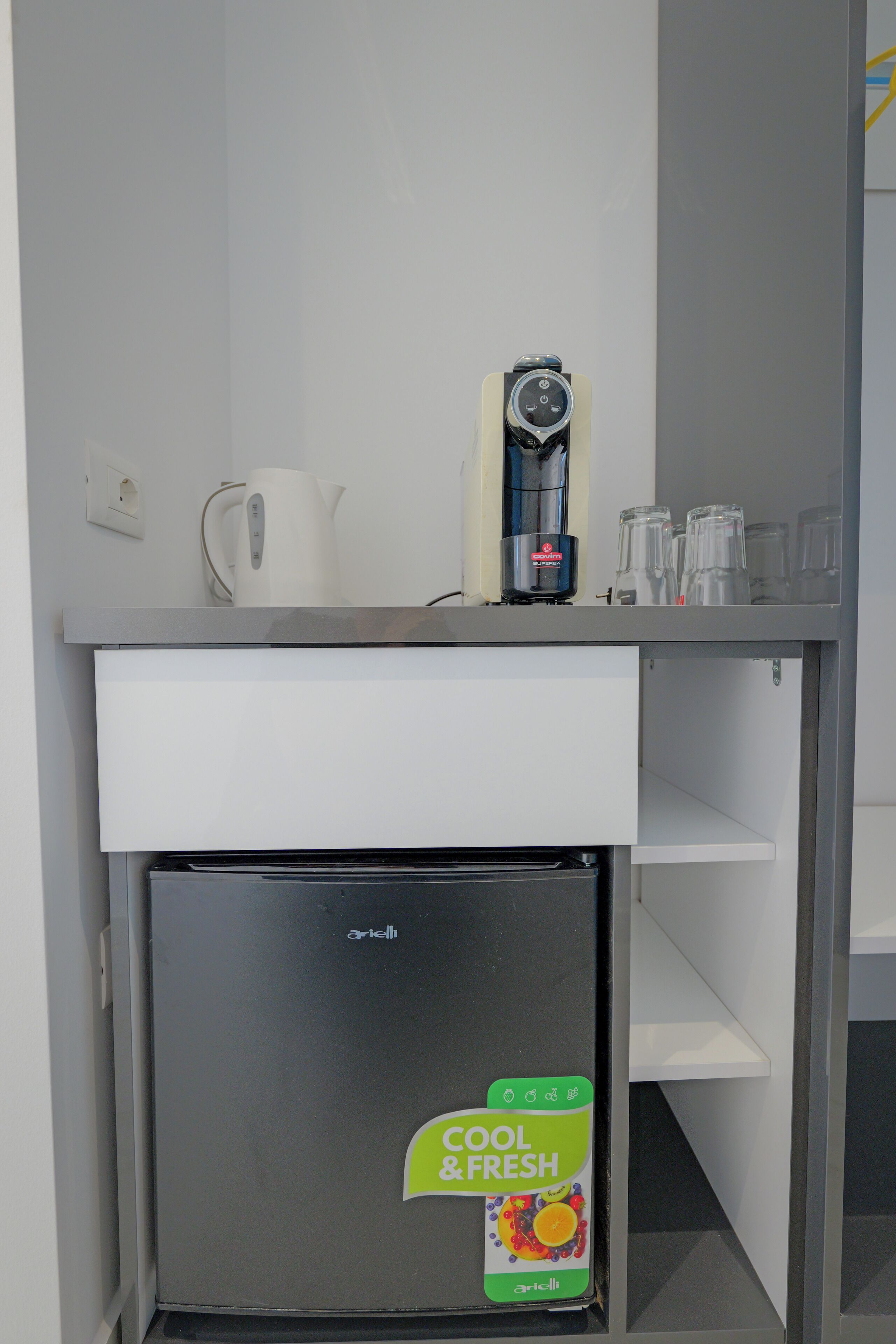 A compact kitchenette with a mini-fridge, a coffee maker, and a kettle.