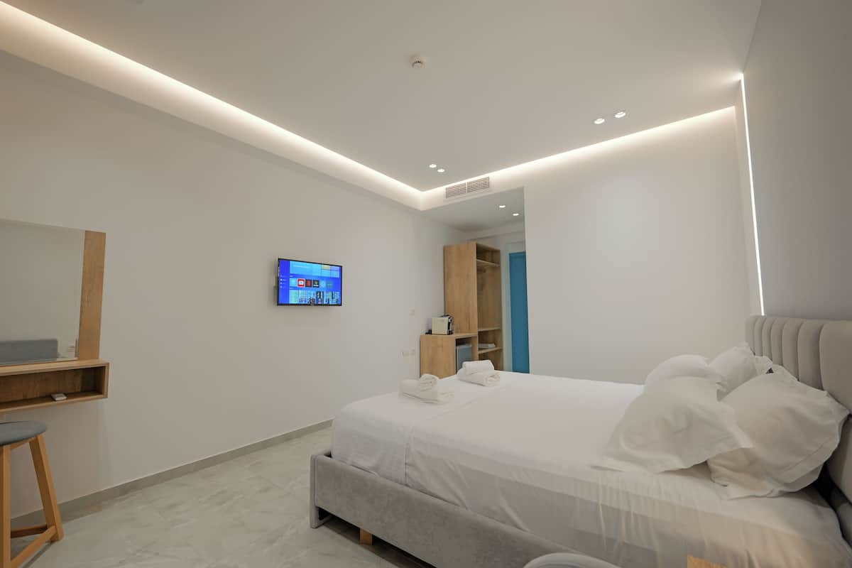 Un dormitorio moderno con una cama, un televisor instalado en la pared y un estante de madera.