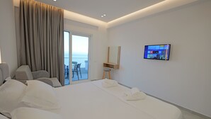 Een moderne hotelkamer met een groot bed, een aan de muur bevestigde televisie, een balkon met een stoel en een schuifdeur.