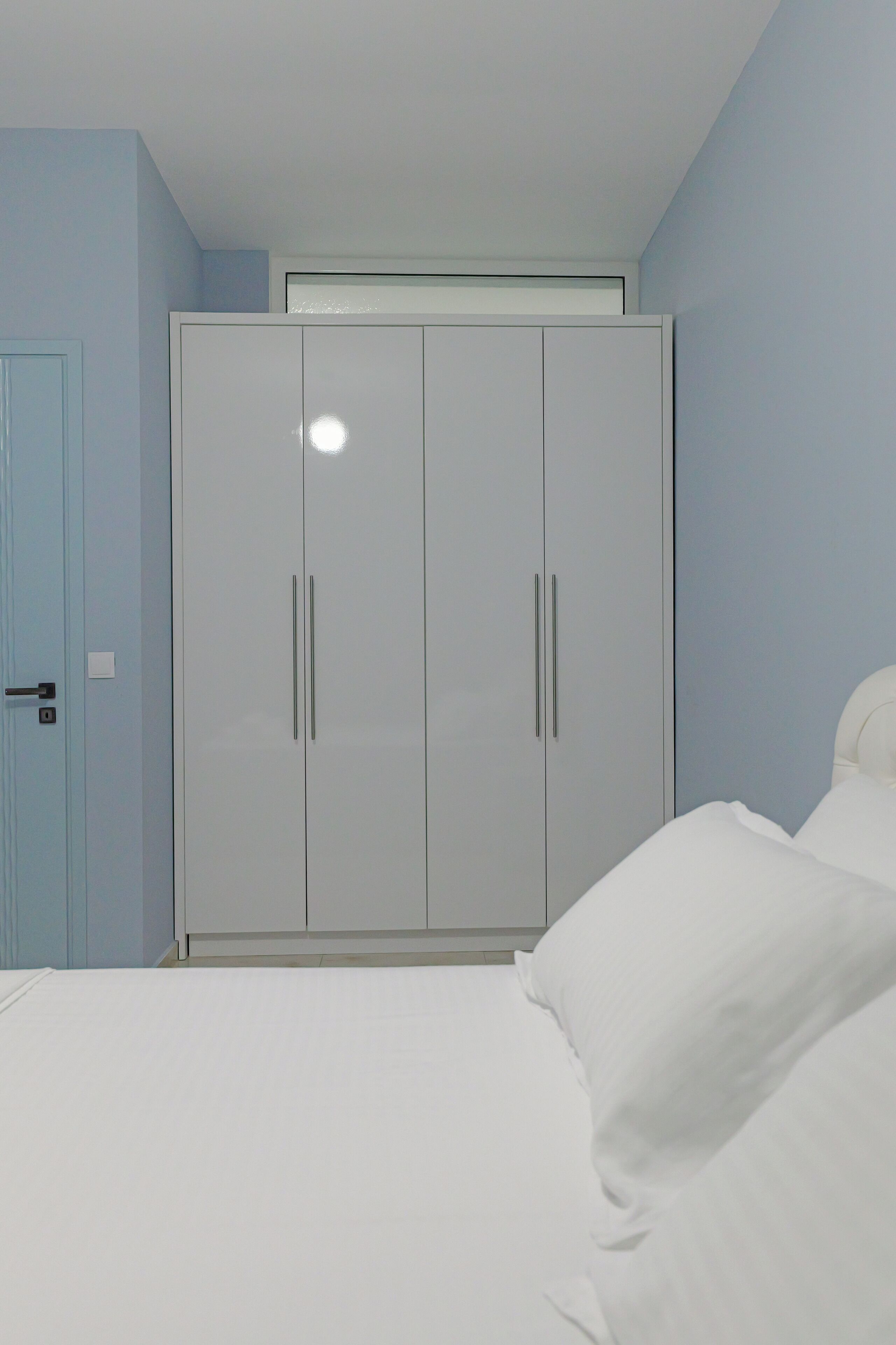 A bedroom with a bed, a wardrobe, and a door.