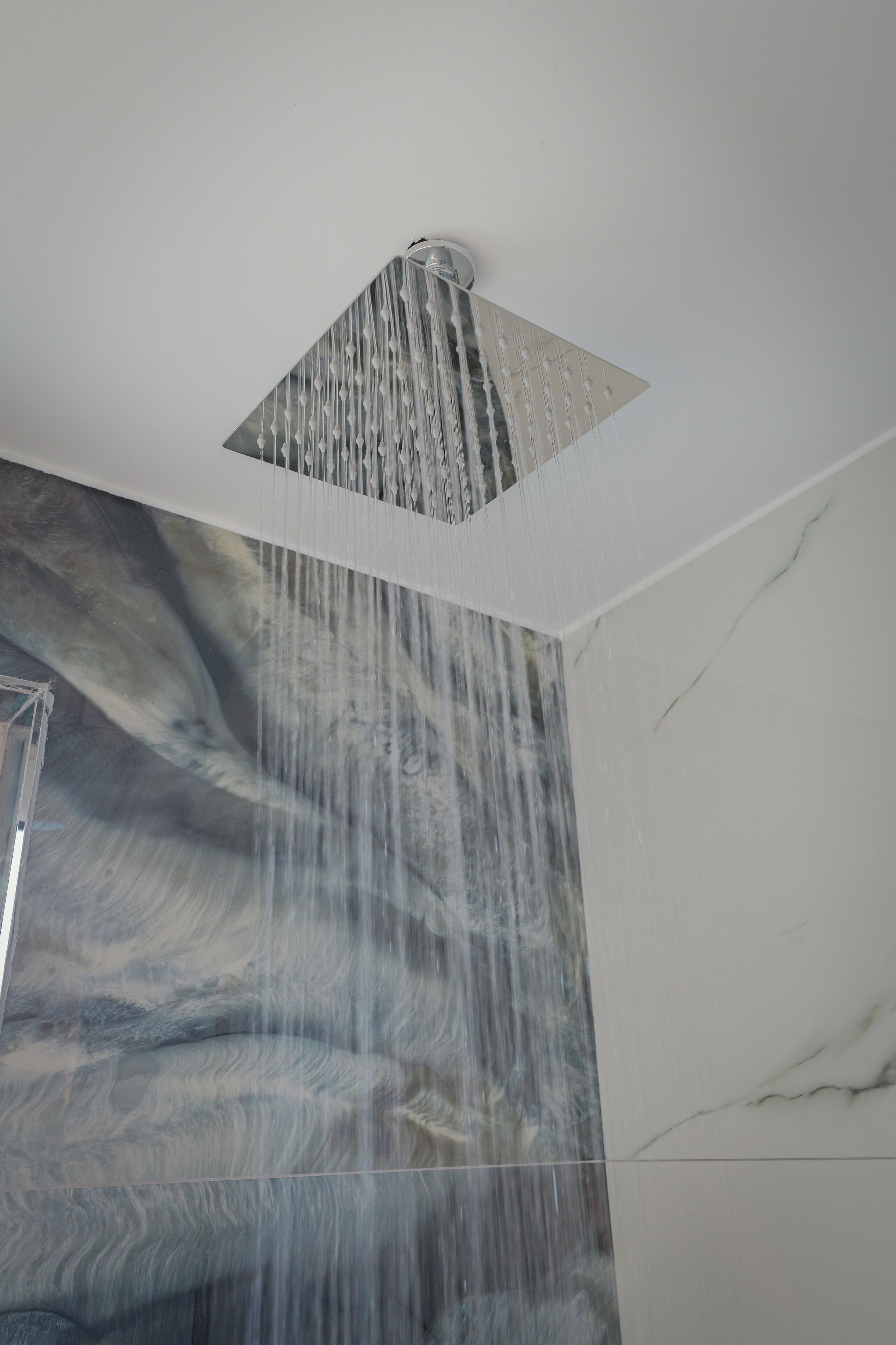 A modern shower with a square design and a waterfall feature.