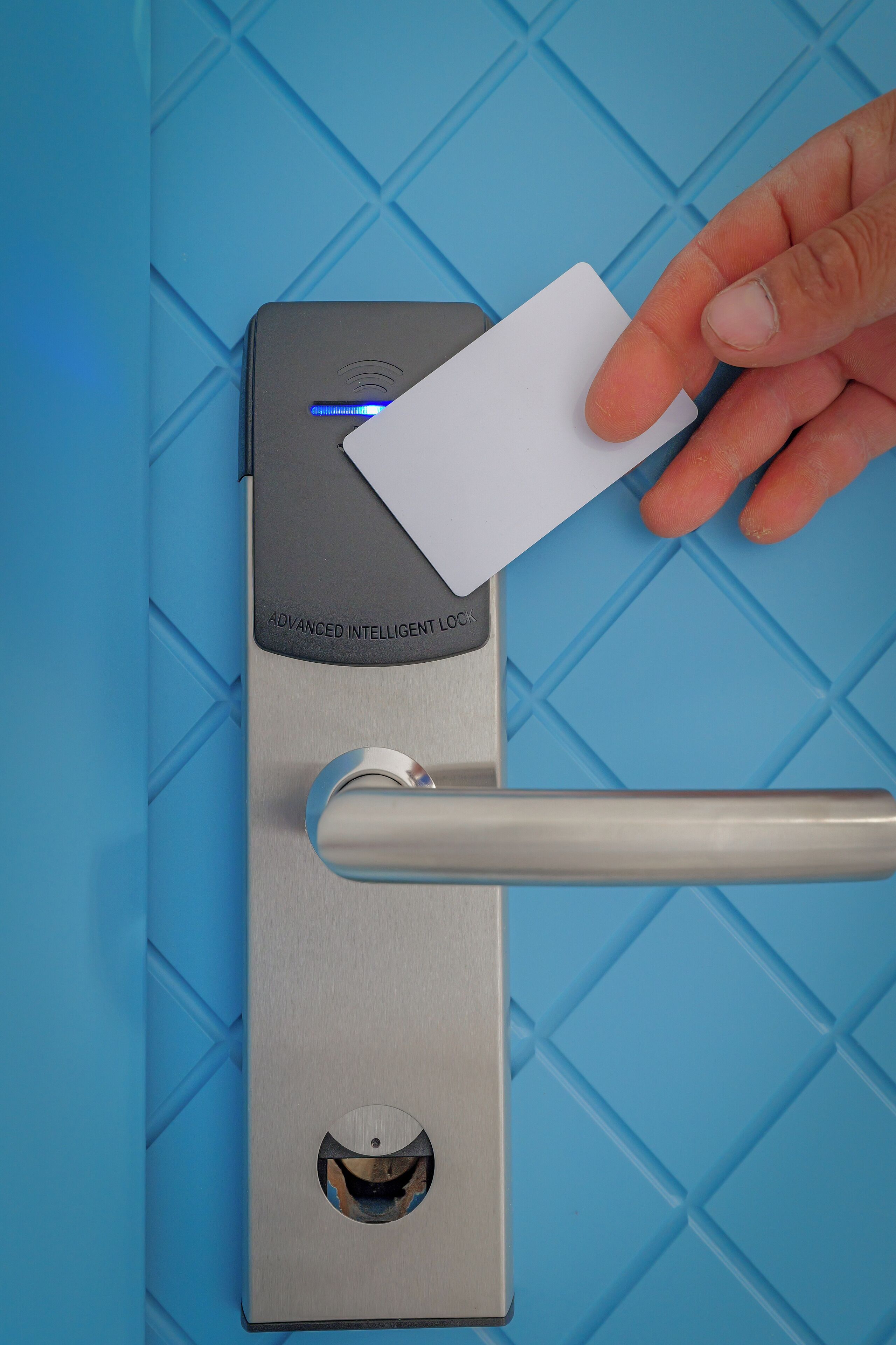 Une main insère une carte dans une serrure intelligente de haute technologie sur une porte.