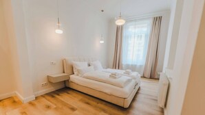 Une chambre moderne avec un grand lit, des tables de chevet et une fenêtre avec des rideaux.