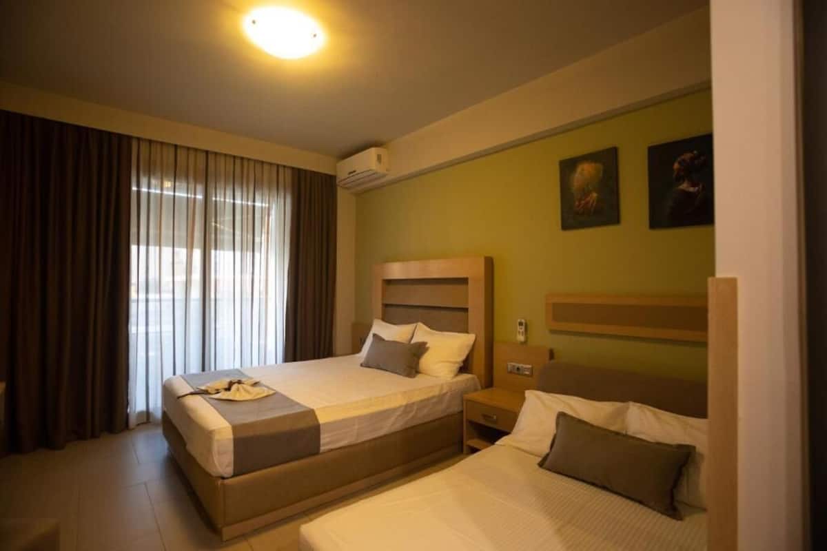 Et hotelværelse med to senge, et natbord, en aircondition og gardiner.
