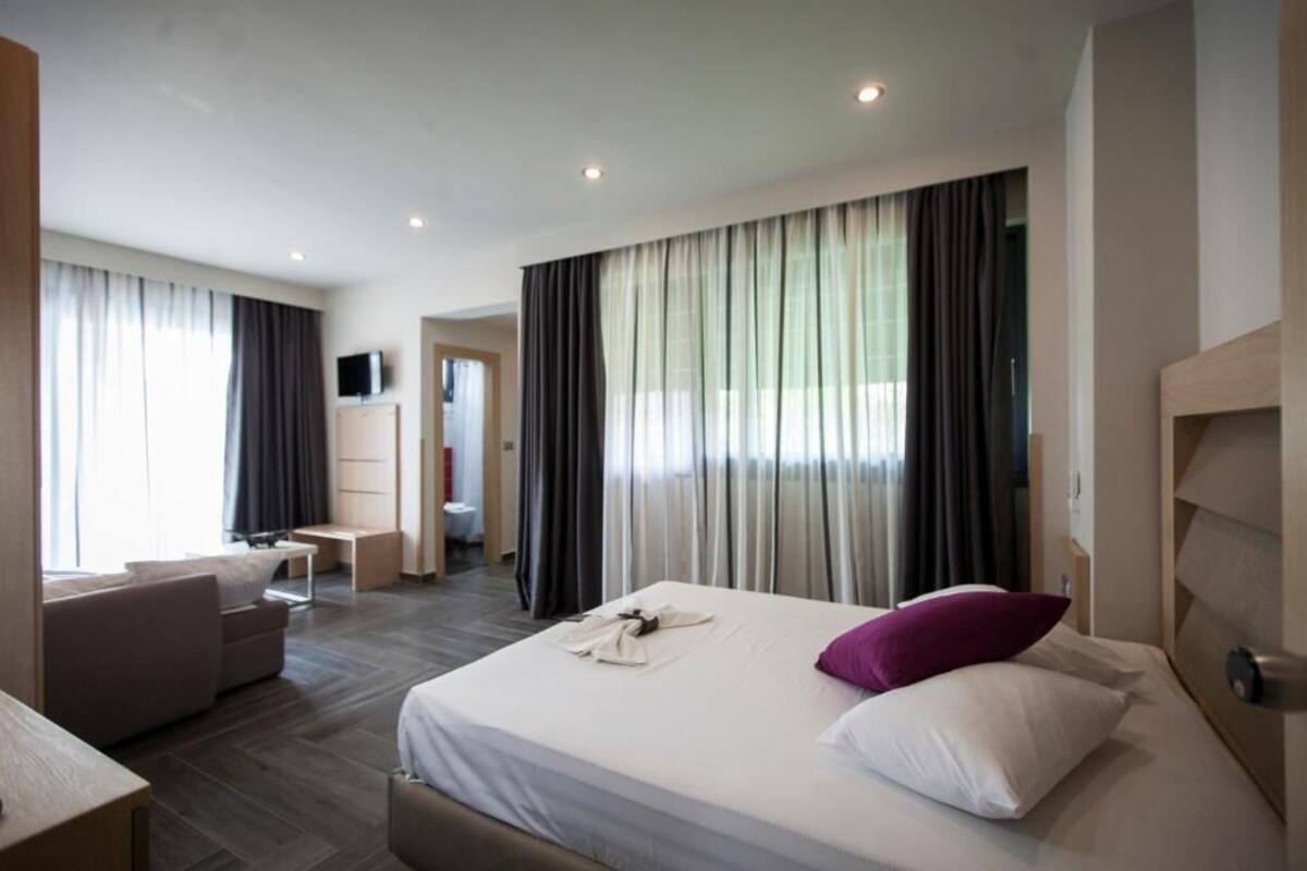 Et moderne hotelværelse med en stor seng, et skrivebord og en sofa.