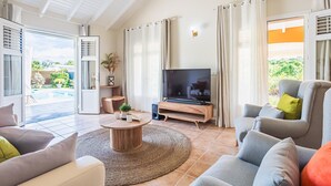 A living room with a TV, sofa, and a coffee table. - Villa Sugar Cane: Pool and Jacuzzi (Le Moule)